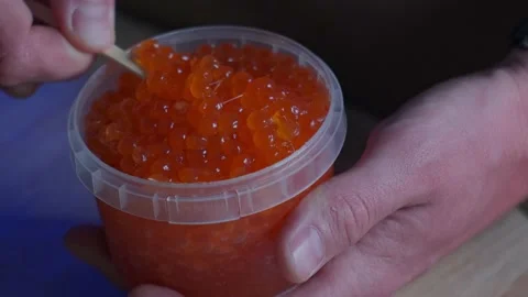 A man mixes red caviar in a jar Stock Footage 179987488