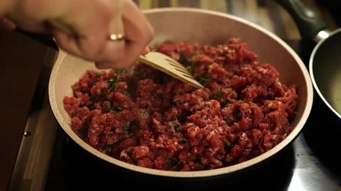 Man mixes steaming minced meat with herbs with a spatula in a frying pan on a Stock Footage 270286505