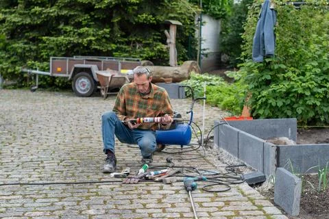 Man mixes two components of adhesive in caulking gun to attach steel support Stock Photos