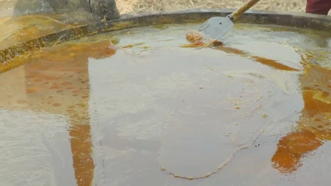 A man mixing and making jaggery in an iron vessel Stock Footage 221888921