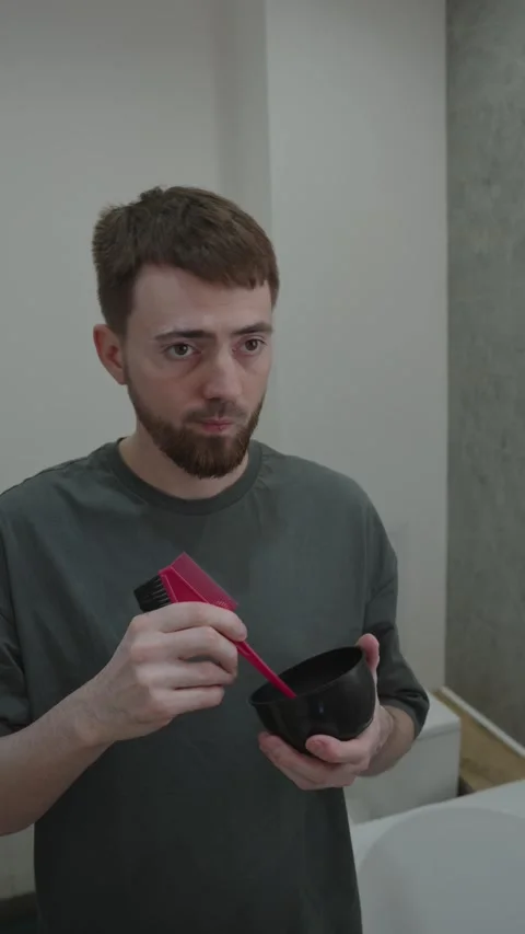 Man mixing and preparing beard dye with care on bathroom counter 動画素材 333332289