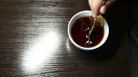 Man mixing a teaspoon of sugar in a cup of tea Stock Footage 53975402