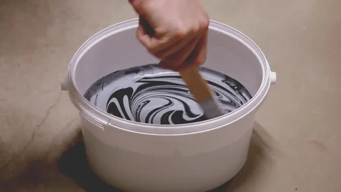 Man mixing two paint colors in bucket Stock Footage 81213738