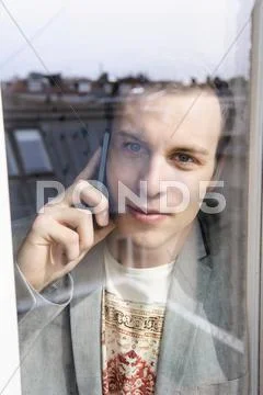 Man On Mobile Phone Behind Window
