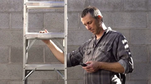 Man With Mobile Phone Puts Down Ladder Stock Footage 71929476