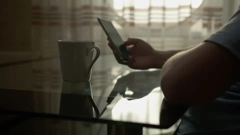 A man with a mobile phone is sitting at a table with a mug of hot coffee Stock Footage 134695135