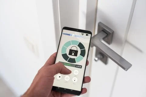 Man with mobile phone using smart home security system application Stock Photos