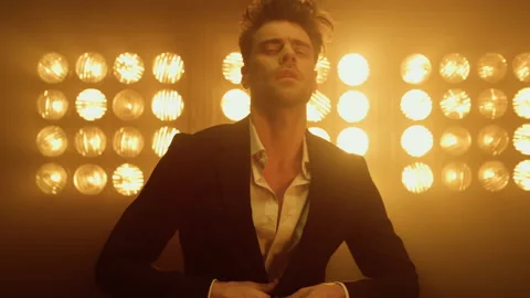 Man model wearing suit buttoning jacket in club lights. Guy posing in studio. Video stock 175352315