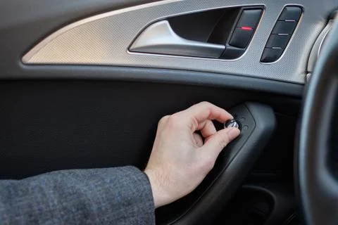 A man in a modern car. Hand pulls the lever to adjust the side mirrors of the Stock Photos