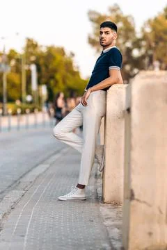 Man in modern clothes posing while leaning on a wall outdoors Stock Photos