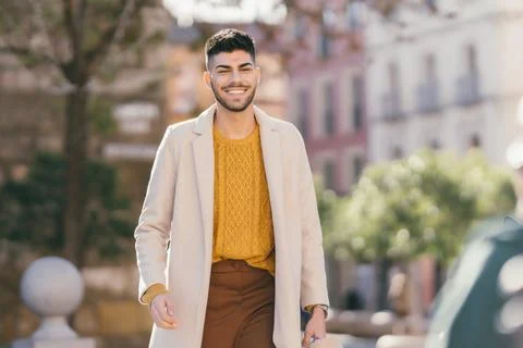 Man in modern clothes walking while smiling in the street Stock Photos