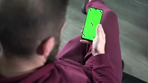 Man at Modern Room Sitting on a sofa Using Phone With Green screen. Relaxed man Video stock 166002793