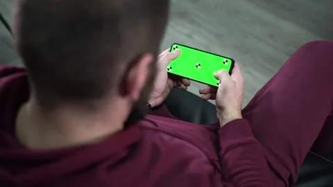 Man at Modern Room Sitting on a sofa Using Phone With Green screen. Relaxed man Video stock 166002895