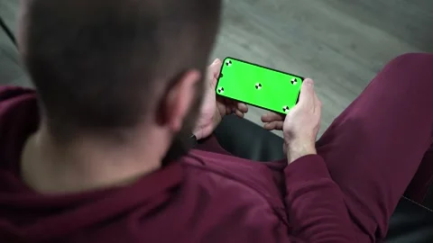 Man at Modern Room Sitting on a sofa Using Phone With Green screen. Relaxed man Video stock 166002955