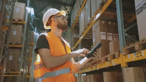 A man in a modern warehouse. The warehouse manager inspects the warehouse 動画素材 312622917
