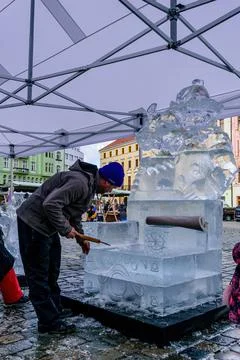 A man is modifying a statue of ice at a carnival in Olomouc 스톡 사진
