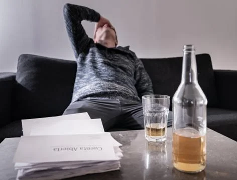 A man with money problems with a Bills stack and alcohol on the table Stock Photos