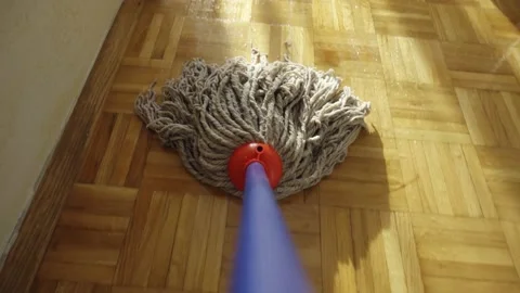 A man is mopping the floor with a mop. The camera is mounted on a mop. Close up. Stockbeeldmateriaal 221558633