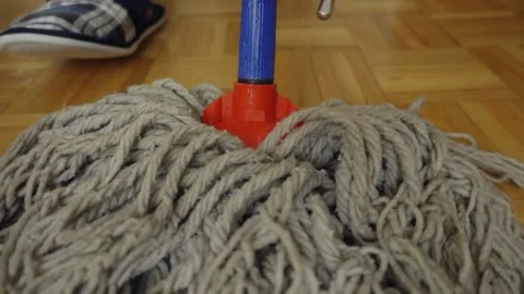 A man is mopping the floor with a mop. The camera is mounted on a mop. Close up. Stockbeeldmateriaal 221558804