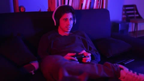 A man with a more serious tone in a medium shot plays video games in his apartme Stock Footage 199128912