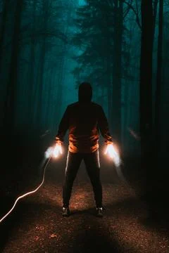Man in motion makes a line of fire behind him with his hands in a mysterious  Stock Photos