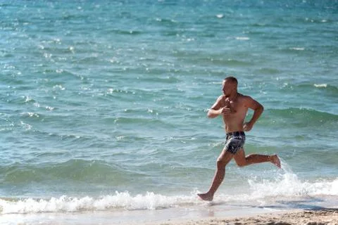 Man in motion of running on beach Stock Photos