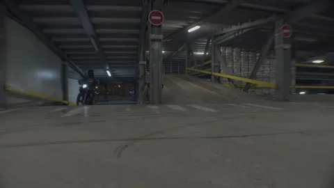 Man on motorcycle drives up to next level of parking lot Stock Footage 290513640