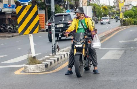 A man with a motorcycle is standing at an intersection Stock Photos