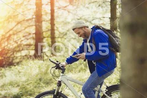 Man Mountain Biking Texting With Cell Phone In Woods