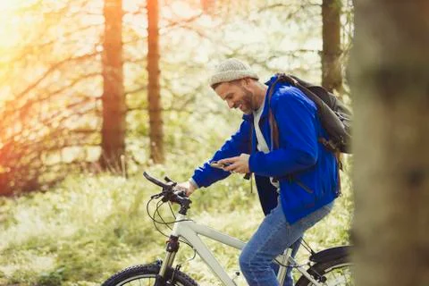 Man mountain biking texting with cell phone in woods Stock Photos
