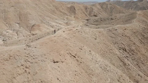 Man mountain biking through a sharp edge mountain ridge in the desert, Israel 스톡 동영상 239760015