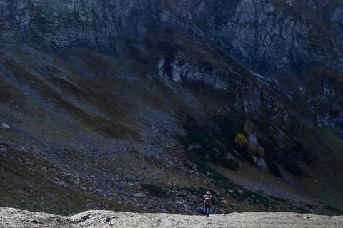A man on a mountain path, a huge rock and a tiny human figure, Foto stock