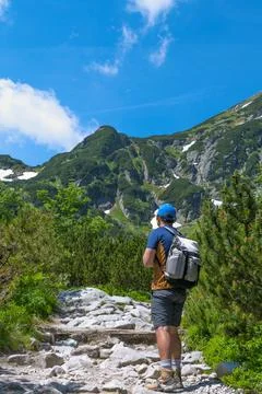 A man on a mountain path in summer. Hiking in the mountains. Active leisure.. Stock Photos