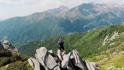 Man on mountain summit among rocks with alpine ridges panorama Stock Footage 336132591