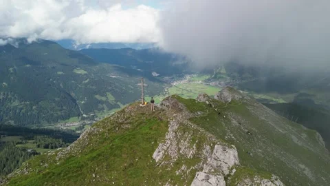 Man on mountain top next to summit cross 動画素材 307690150