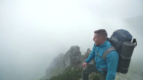 A man in the mountains in cloudy weather stood on a rock, rejoices in victory Stock Footage 218438688