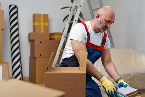 Man mover in uniform packing boxes for relocation Stock Photos