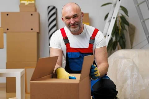 Man mover in uniform packing boxes for relocation Stock Photos