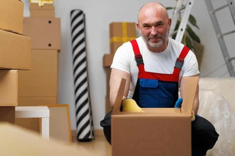 Man mover in uniform packing boxes for relocation Stock Photos