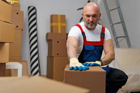 Man mover in uniform packing boxes for relocation Stock Photos