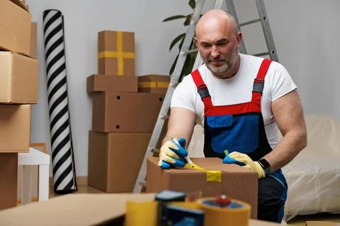 Man mover in uniform packing boxes for relocation Stock Photos