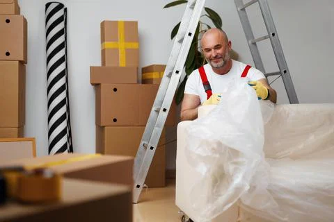Man mover in uniiform packing sofa for relocation Stock Photos