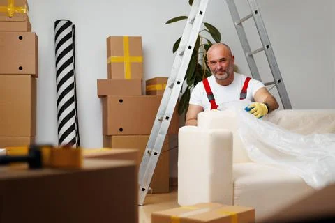 Man mover in uniiform packing sofa for relocation Stock Photos