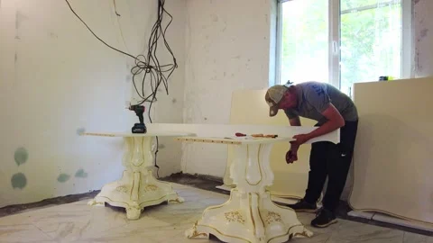Man moves and sets up large table in unfinished room with tools Stock Footage 340357269