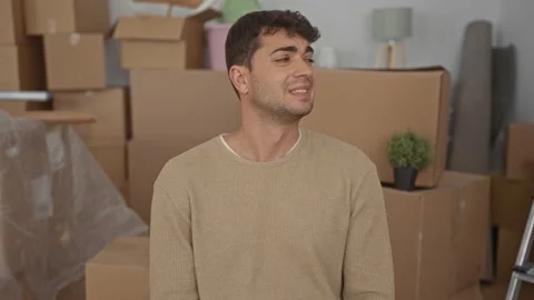 Man moves boxes then arranges them in home while hispanic unpacks new movin.. Stock Footage 310985800