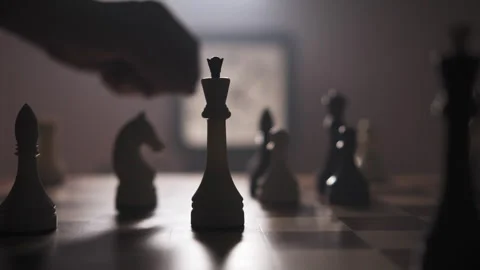 A man moves chess pieces on a chessboard in a dimly lit room Stock Footage 312824818