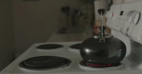 Man moves tea kettle on stove in kitchen Stock Footage 78038232