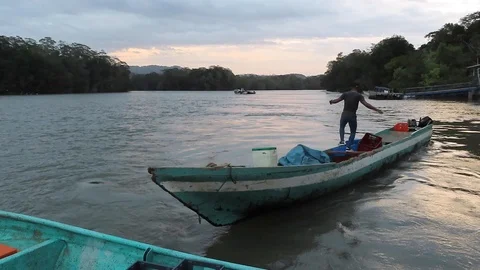 Man moving about on a small boat on the river Stock Footage 111233501
