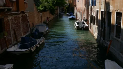 Man moving boxes &amp; stuff from boat to his house in the middle of water canal Stock Footage 68991460