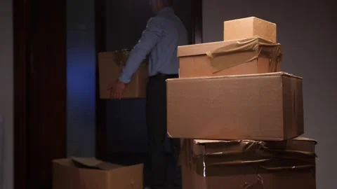 Man moving cardboard boxes during house relocation process Video stock 318980340